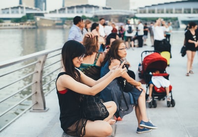 穿着黑色圆领无袖衬衫的女人坐在栏杆旁边的地板上，拿着小工具
